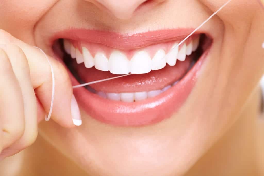 Woman with nice teeth, using dental floss