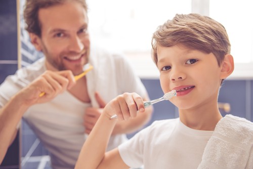 man and son brushing teeth together